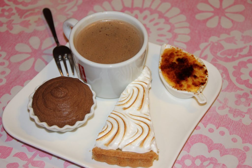 café gourmand au déjeuner sur l'herbe, assiette blanche avec une tasse à café et des petits gâteaux cambo les bains