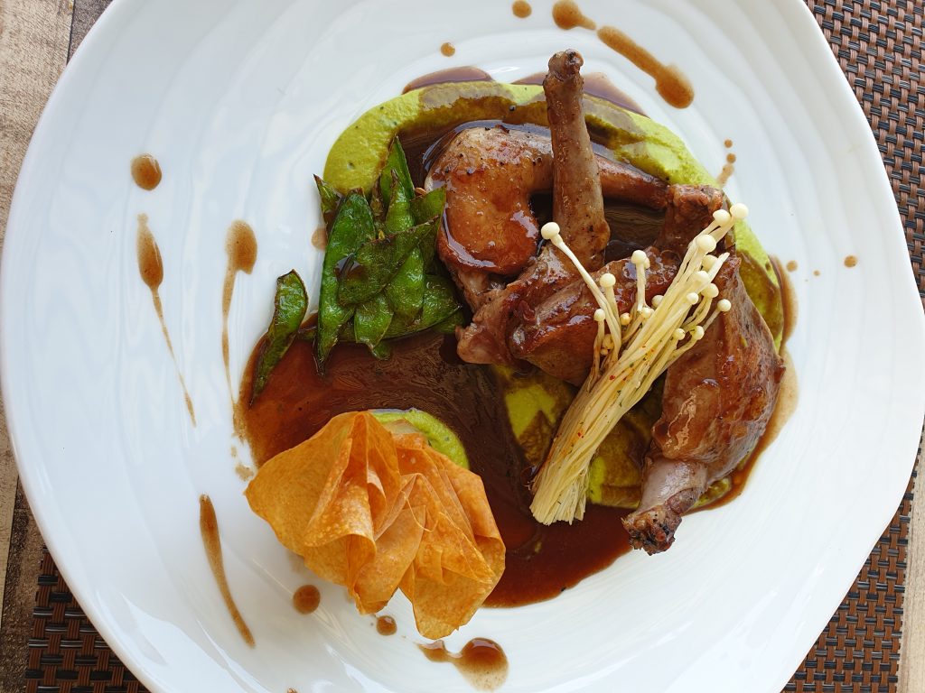 assiette blanche avec 1/2 pigeonneau avec une purée de petits pois